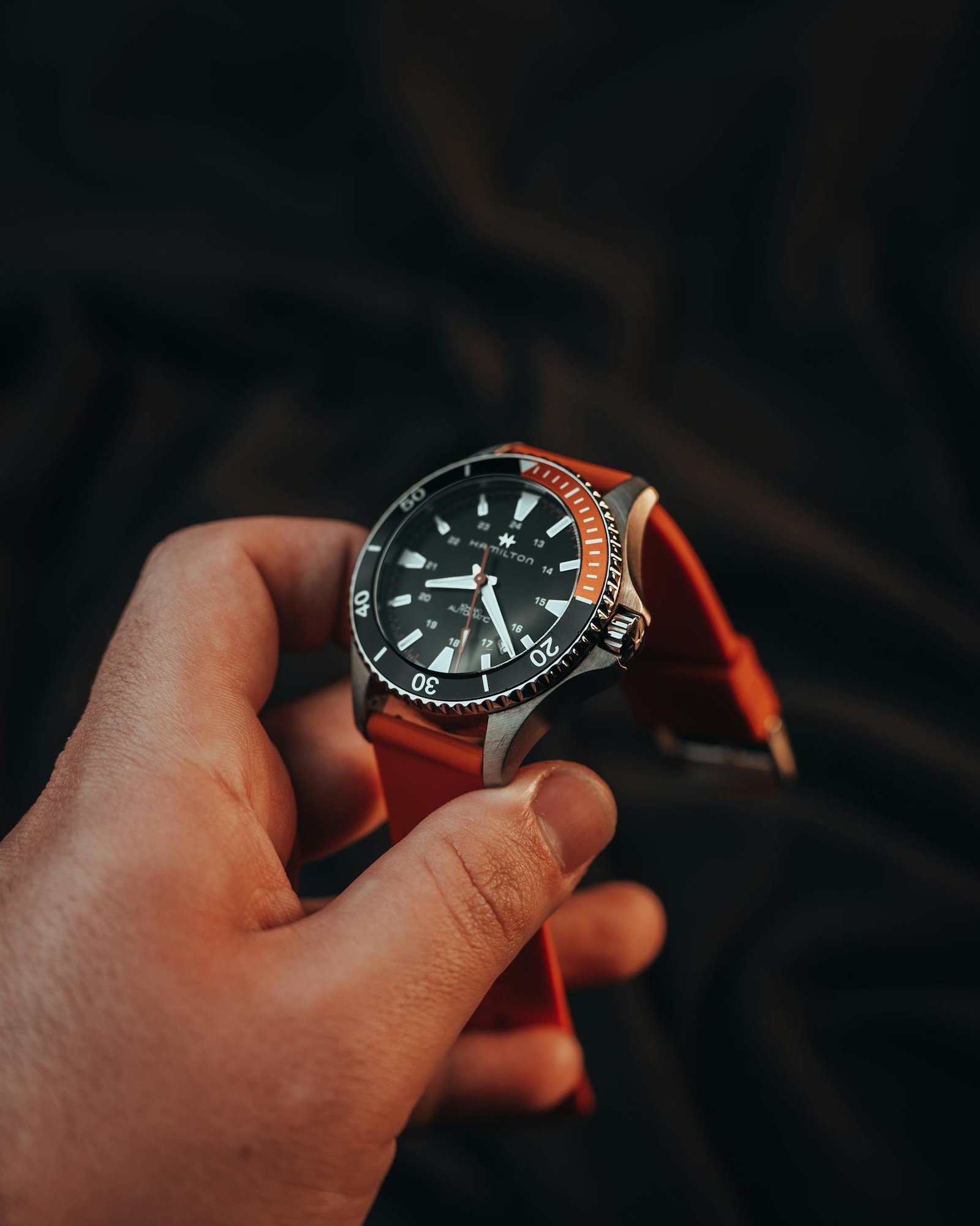 A luxury scuba diving watch with a red strap captured in a close-up shot, symbolizing wealth and style.